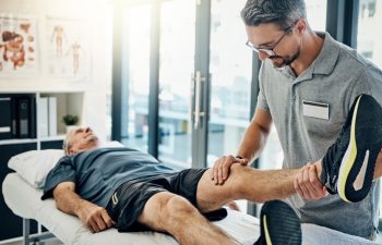 Physiotherapist, senior man and stretching leg for knee pain, medical and consultant with injury support. Consultation, chiropractor and physical therapy with rehabilitation and care in doctor office